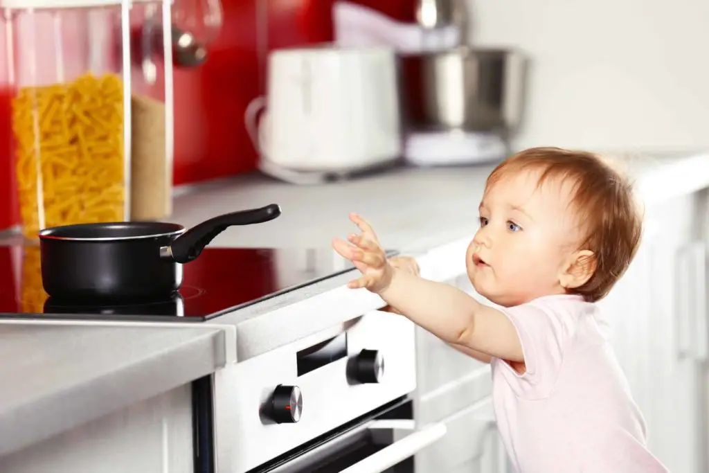 Ttoddler reaching towards a pot on a stove